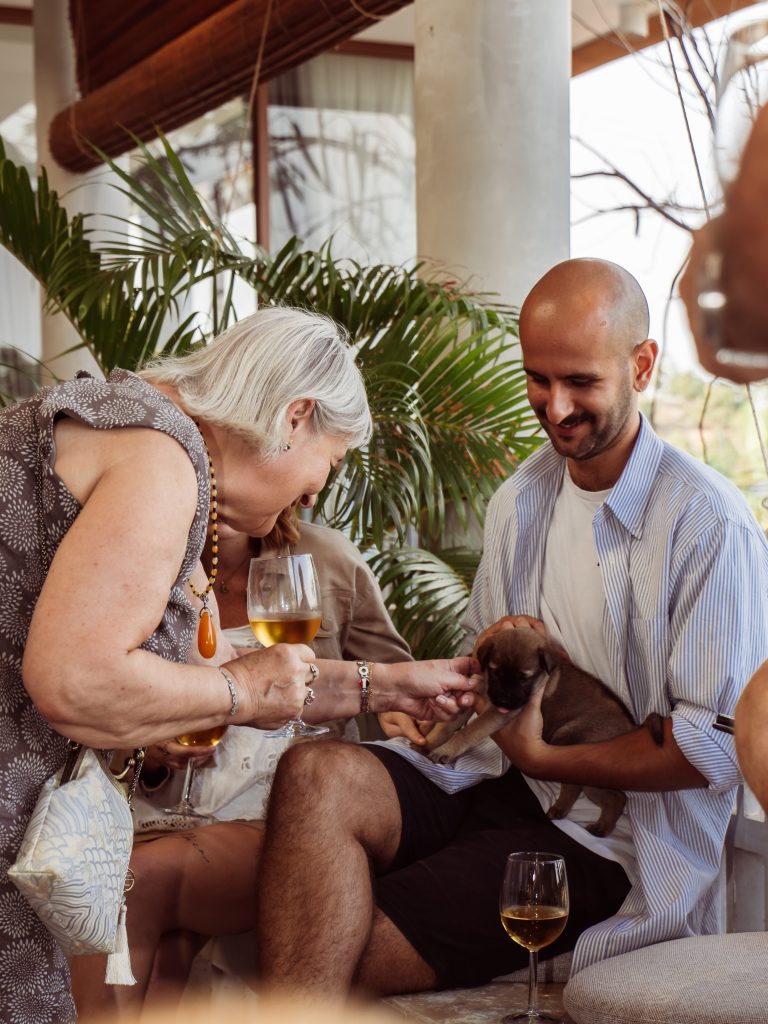 Des invités partageant un moment complice en jouant avec un chiot à la villa Amaya