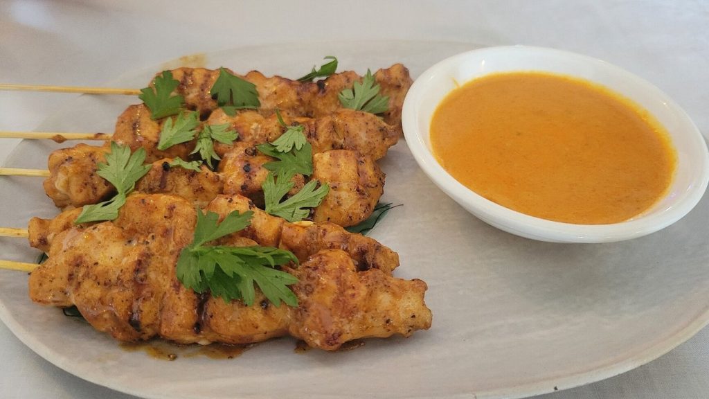 Ce plat est un poulet satay, une entrée populaire d’Asie du Sud-Est composée de brochettes de poulet marinées et grillées, servies avec une sauce aux cacahuètes savoureuse<br srcset=