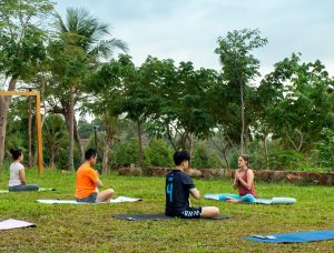 Séance de yoga matinal sur le domaine Amaya avec la végétation luxuriante en arrière-plan.
