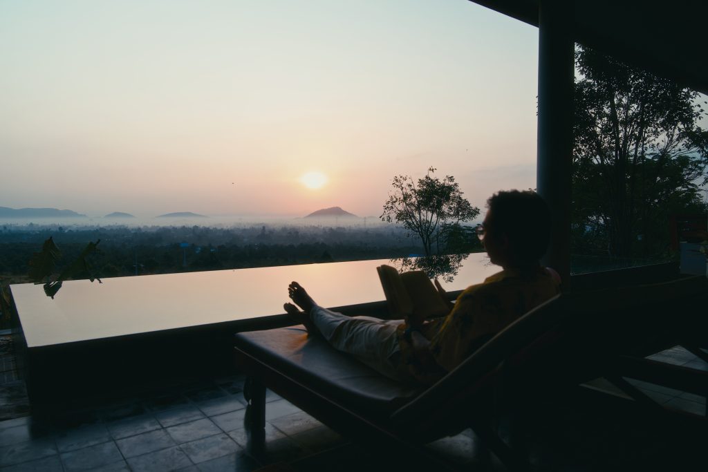 Silhhoutte of a person sitting on one of the tanning beds in Amaya home looking at the sunset and reading