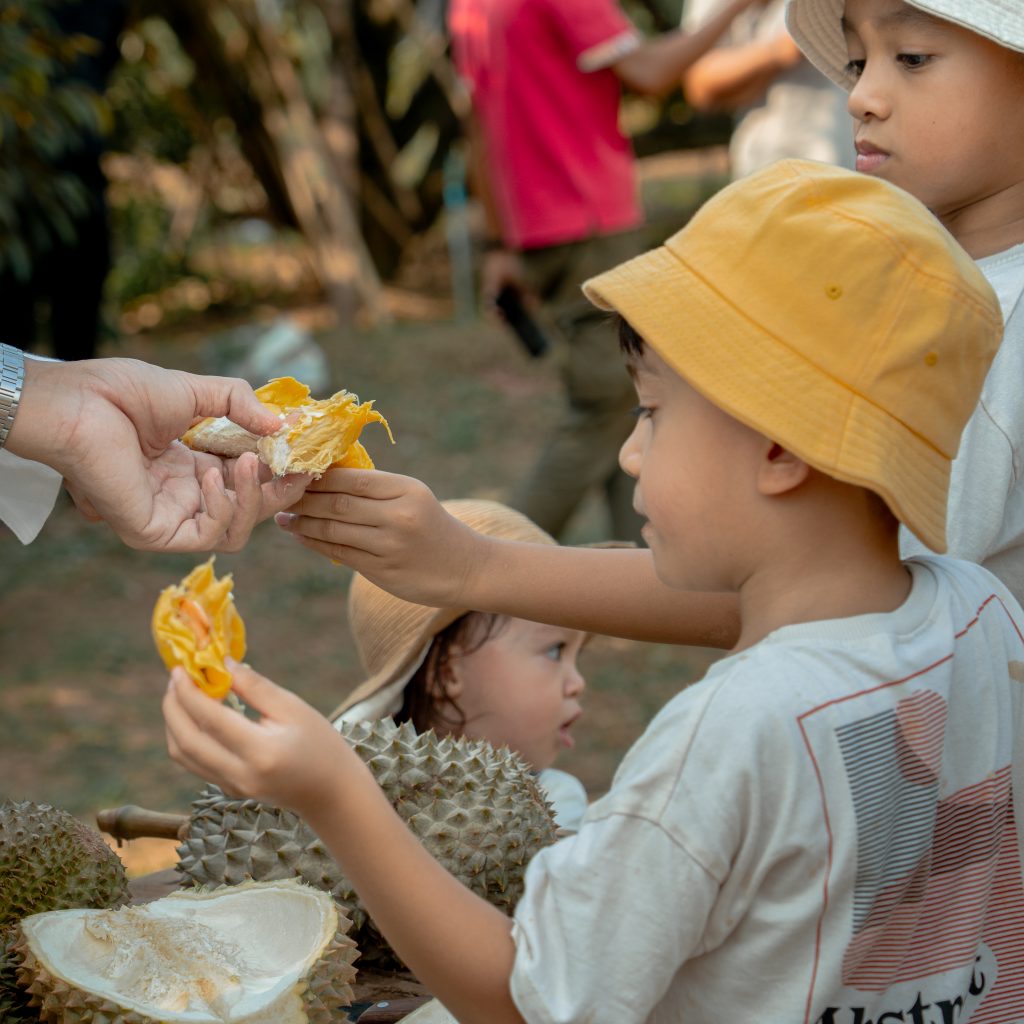 Des enfants dégustant des durians après la visite de la ferme du domaine d'Amaya.